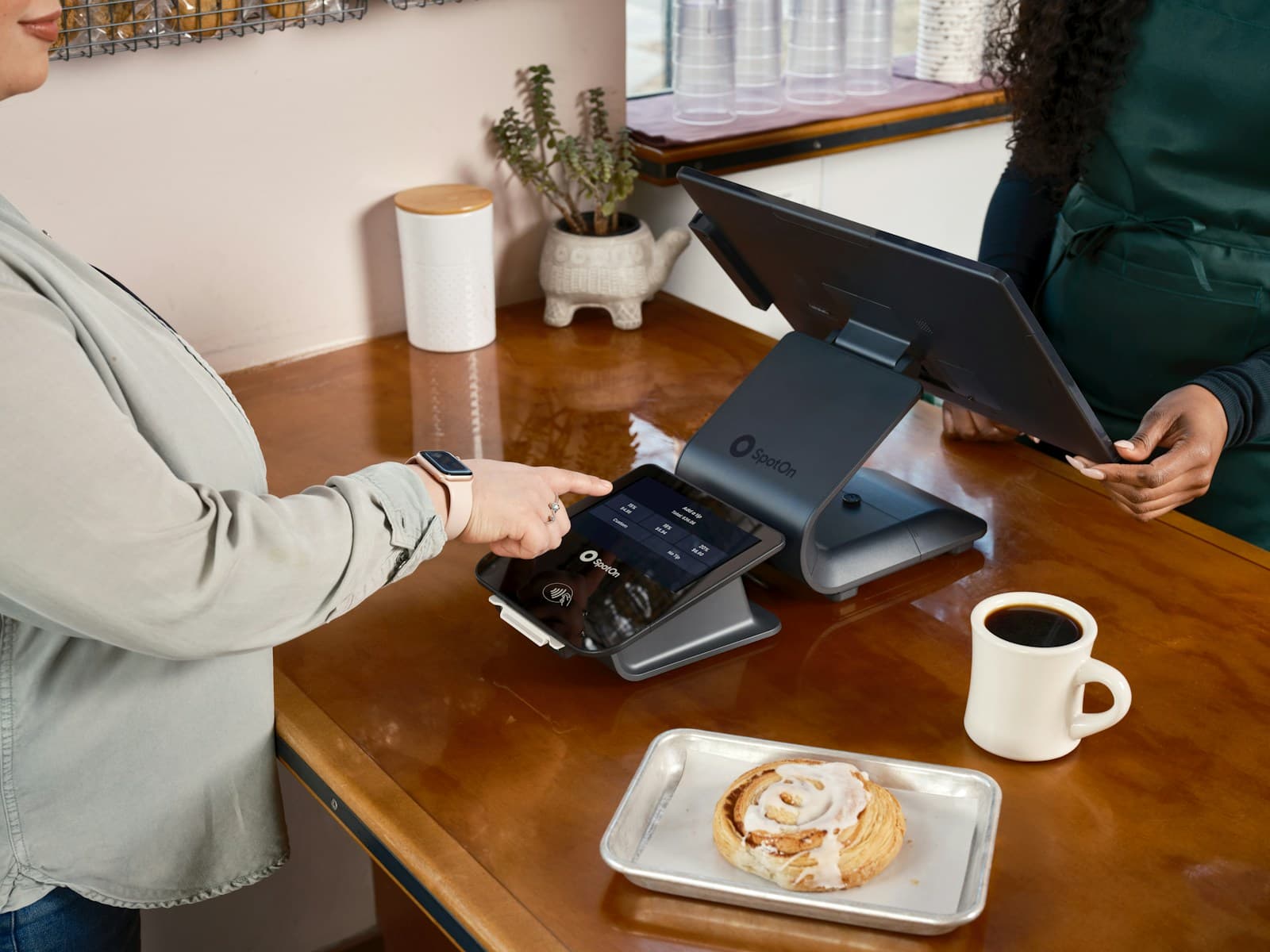 A customer tapping a card on a payment terminal at a cafe counter